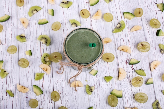 Green detox cocktail staat op tafel met kleine stukjes fruit