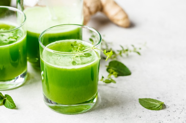 Green detox juice with ginger and mint in glasses and jars 