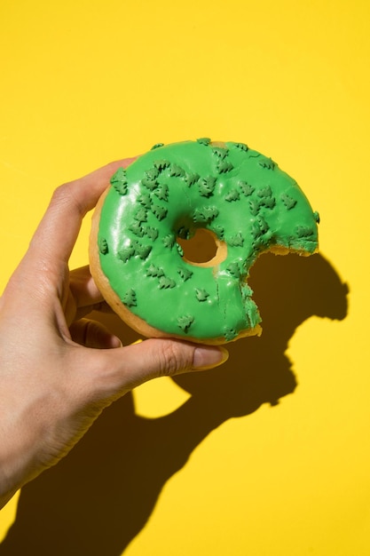 Green donut in hand Photo vertical in studio