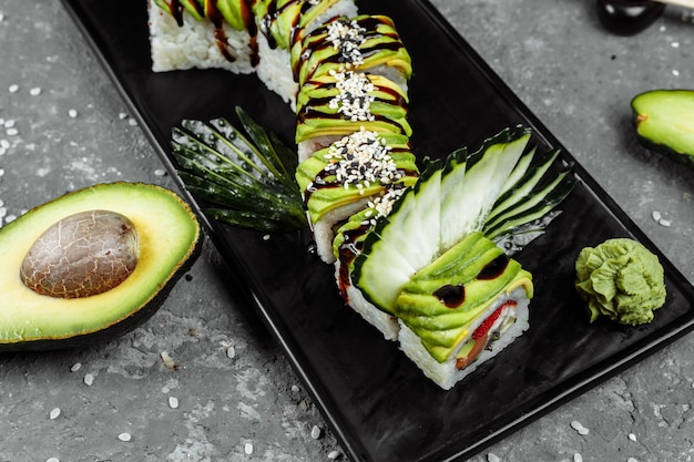 Green dragon sushi roll met paling, avocado, komkommer en gember, vergezeld van gebakken tempura garnaal. Traditionele Aziatische rijst sushi gezonde zeevruchten.