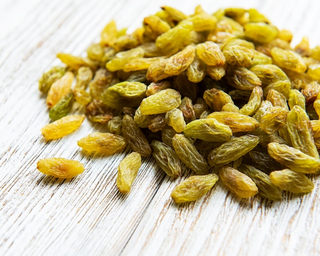 Green dried raisins on a white wooden background