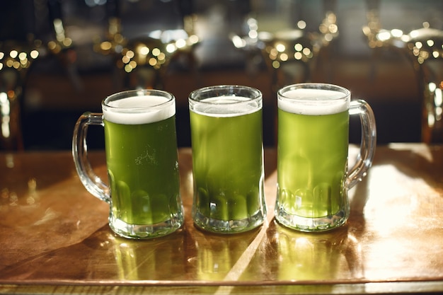 写真 ガラスの緑の飲み物。男の手にガラス。バーでビール。
