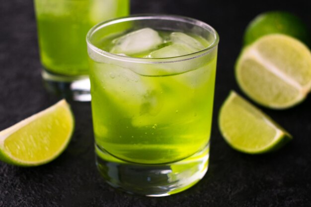 Green drink with lime and ice on a black backgroundCloseup