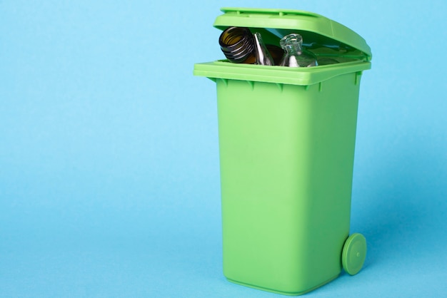 Photo green dustbin on a blue background with waste glass. recycling. ecological concept.