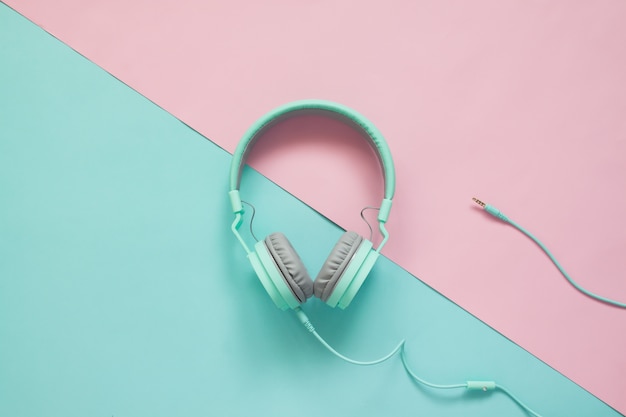 Green earphones on pink and green colors background