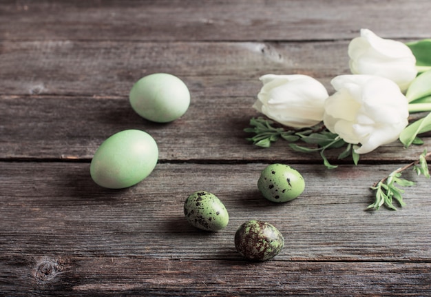 Green easter eggs and tulips on wooden background