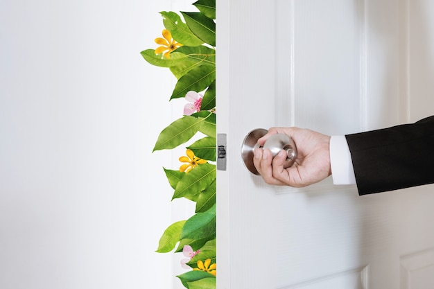 Foto uomo d'affari verde ed ecologico che apre la porta con foglie e fiori