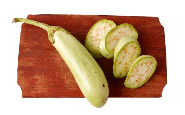 Green eggplant on a wooden cutting board isolated on a white background