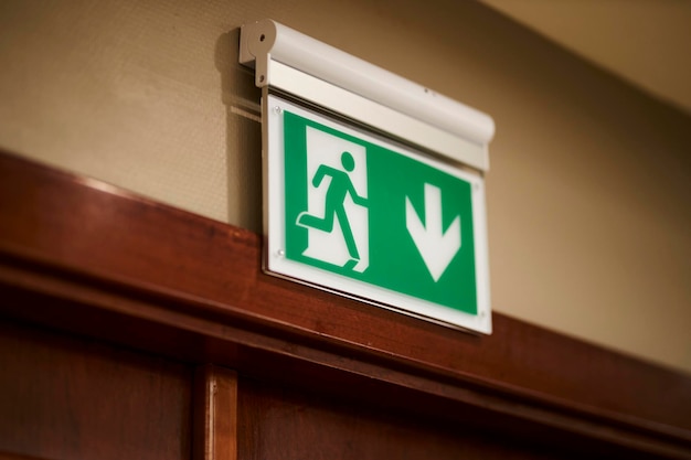 Photo green emergency exit sign above a door in a interior direction to the emergency exit