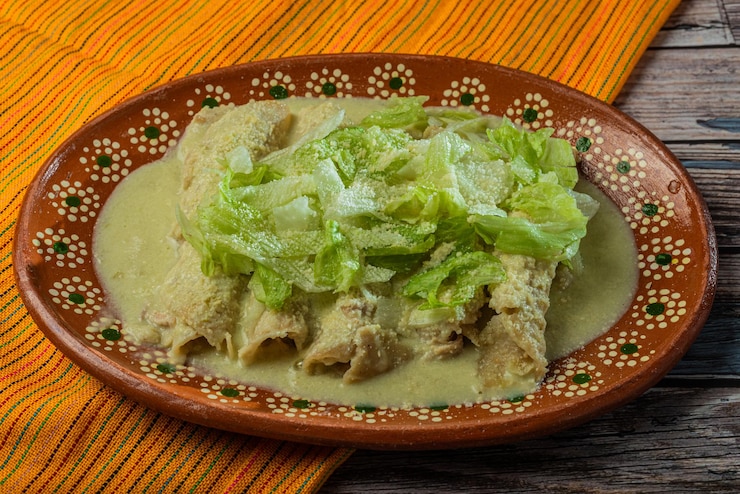 Photo green enchiladas with lettuce served in a clay dish on a wooden table