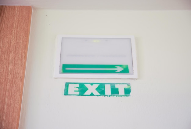 壁に緑色の出口標識があり、出口を示す白い標識が付いています。