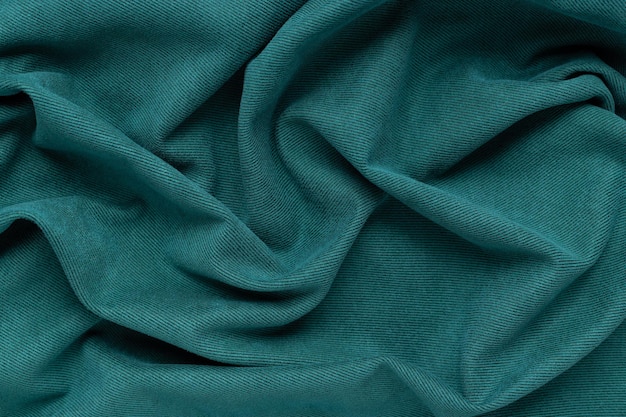 Green fabric background with folds Wavy folds material Textile and texture concept