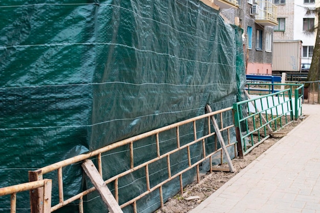 Green fence of construction site near sidewalk