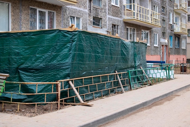 Green fence of construction site near sidewalk