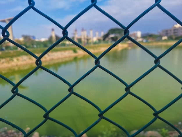 a green fence with a chain link fence that has a view of the city.