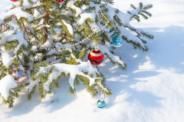 Green festive Christmas tree decorated with toys and beads in the snow. Copy space.