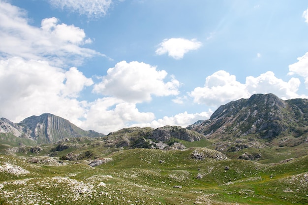 Green field in mountains wide viewblue sky clouds