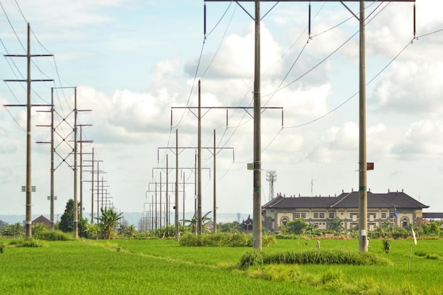 a green field with power lines and a house in the background