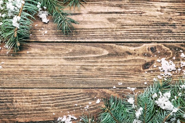 Green fir branches with snow on wooden