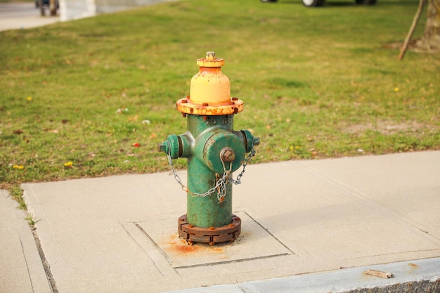 A green fire hydrant with a yellow top and the word fire on it.