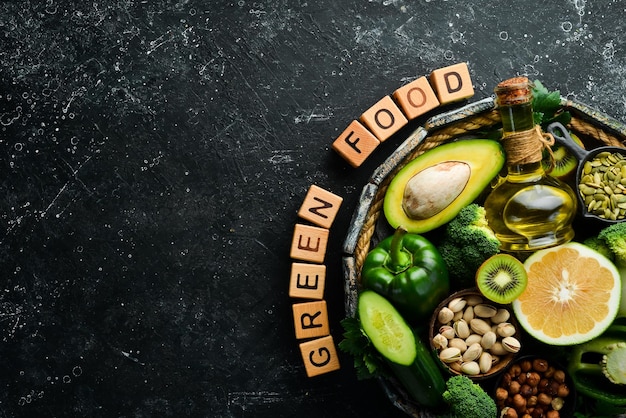 Green foods avocado broccoli parsley celery cucumber and kiwi The inscription Green food Top view Rustic style