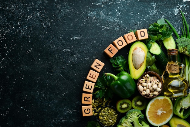 Green foods avocado broccoli parsley celery cucumber and kiwi The inscription Green food Top view Rustic style