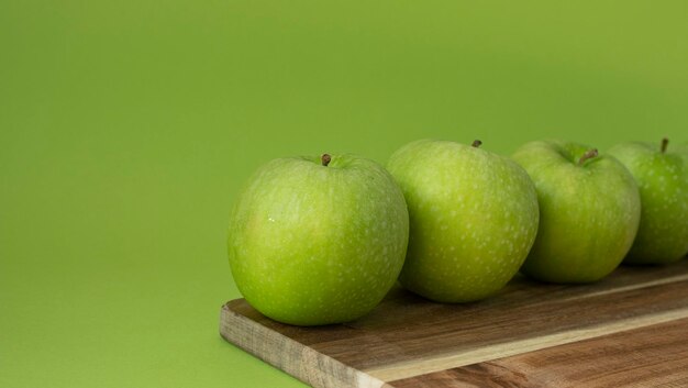 Green and fresh apples on wooden background and on green color