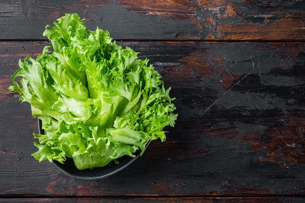 Green fresh lettuce leaves, on old dark wooden table, top view flat lay