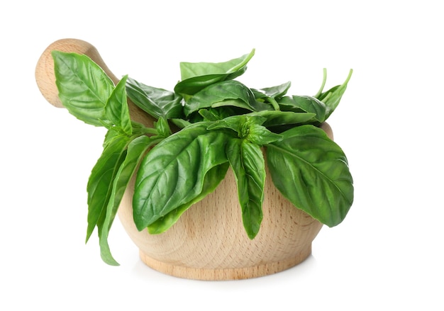 Green fresh organic basil leaves in wooden mortar isolated on white