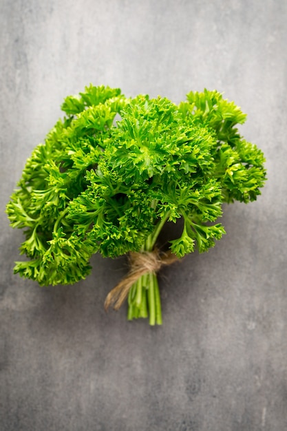 Green, fresh parsley on gray metal surface.