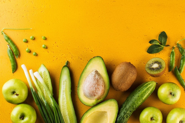 Green fresh vegetables and fruits on yellow