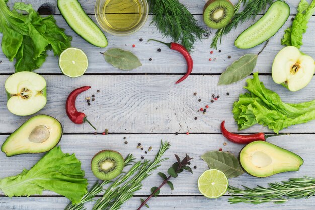 Green fresh vegetables and spices on a white wooden table. Top view. Place for text