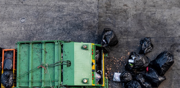 Photo green garbage truck collecting a large number of black garbage bags