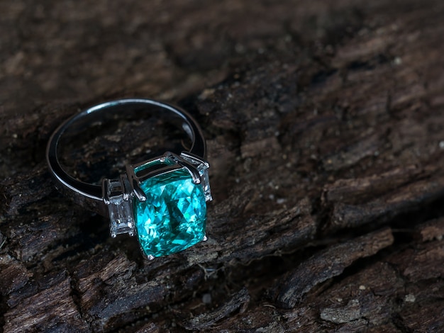 Photo green gem ring with white diamond on old wooden background