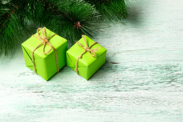 Green gift boxes under the Christmas tree on a wooden floor near fir branches