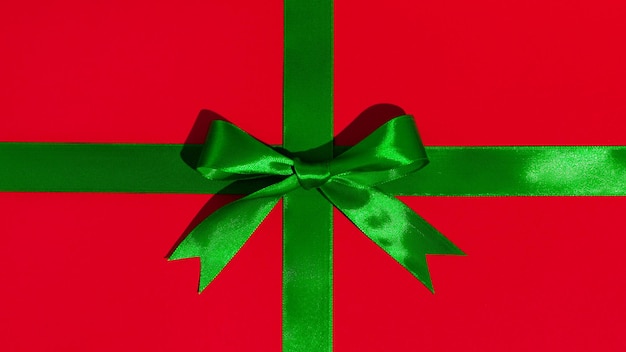 Green gift ribbon and bow on red paper background