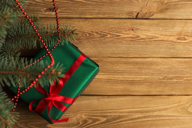 Green gift with red ribbon, Christmas tree and decorations on the table