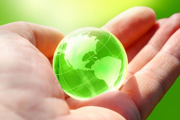 Green Glass globe of the planet Earth in human hand