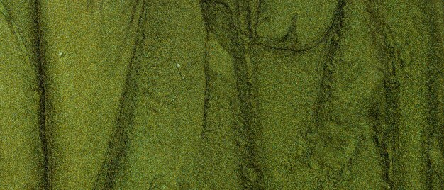 Green glitter texture. Background with brush strokes of shiny oil paints. Sparkling surface with green shades. Earth color concept