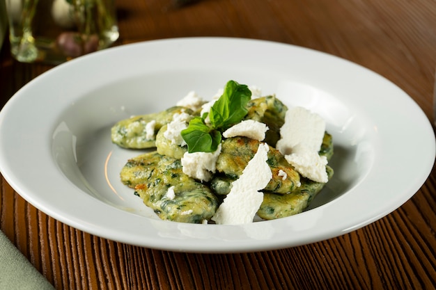 Green Gnocchi with basil, spinach, pesto feta cheese in composition with green cloth and olive oil.
