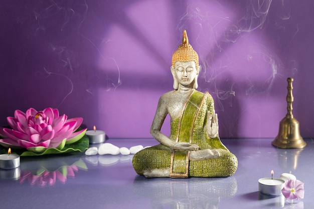 Green and golden buddha statue in meditation on light purple\
background with copy space