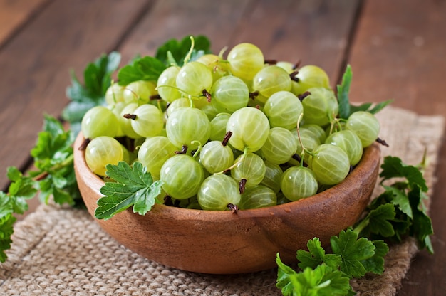 Photo green gooseberries in a wooden bowl