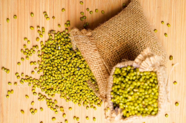 Green gram or mung bean in bag over wooden background.