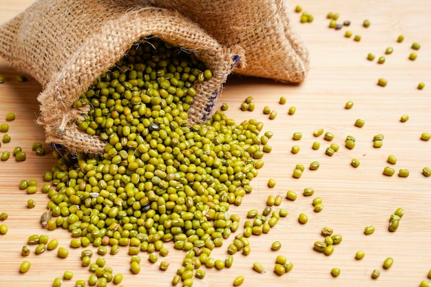 Green gram or mung bean in bag over wooden background.