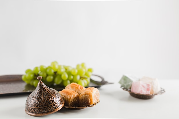 Foto uva verde sul vassoio vicino baklava e delizie turche su piattini