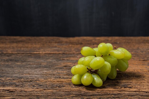 Uva verde con foglie isolate su sfondo di legno completa profondità di campo spazi bianchi per il testo