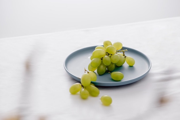 Photo green grapes in a blue dish on the table