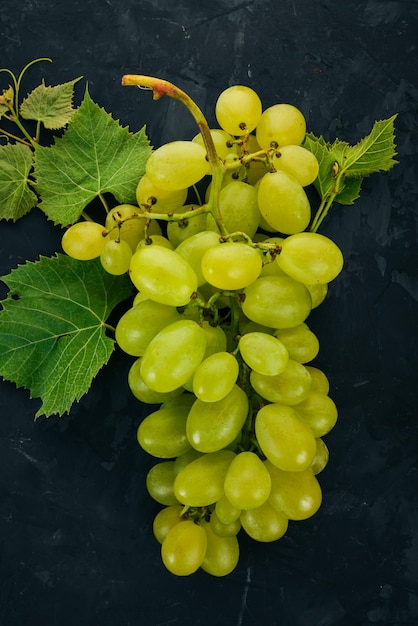 Green grapes with leaves of grapes on a stone table Top view Free space for text