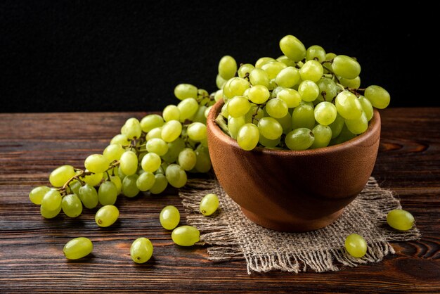 Green grapes on a wooden bowl on the table