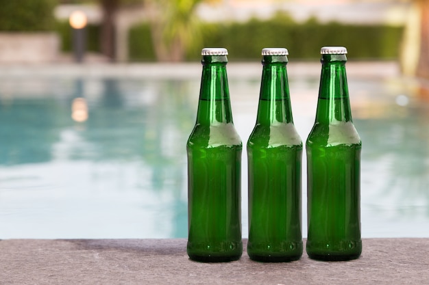 green grass bottle of liquid on rim of swimming pool 